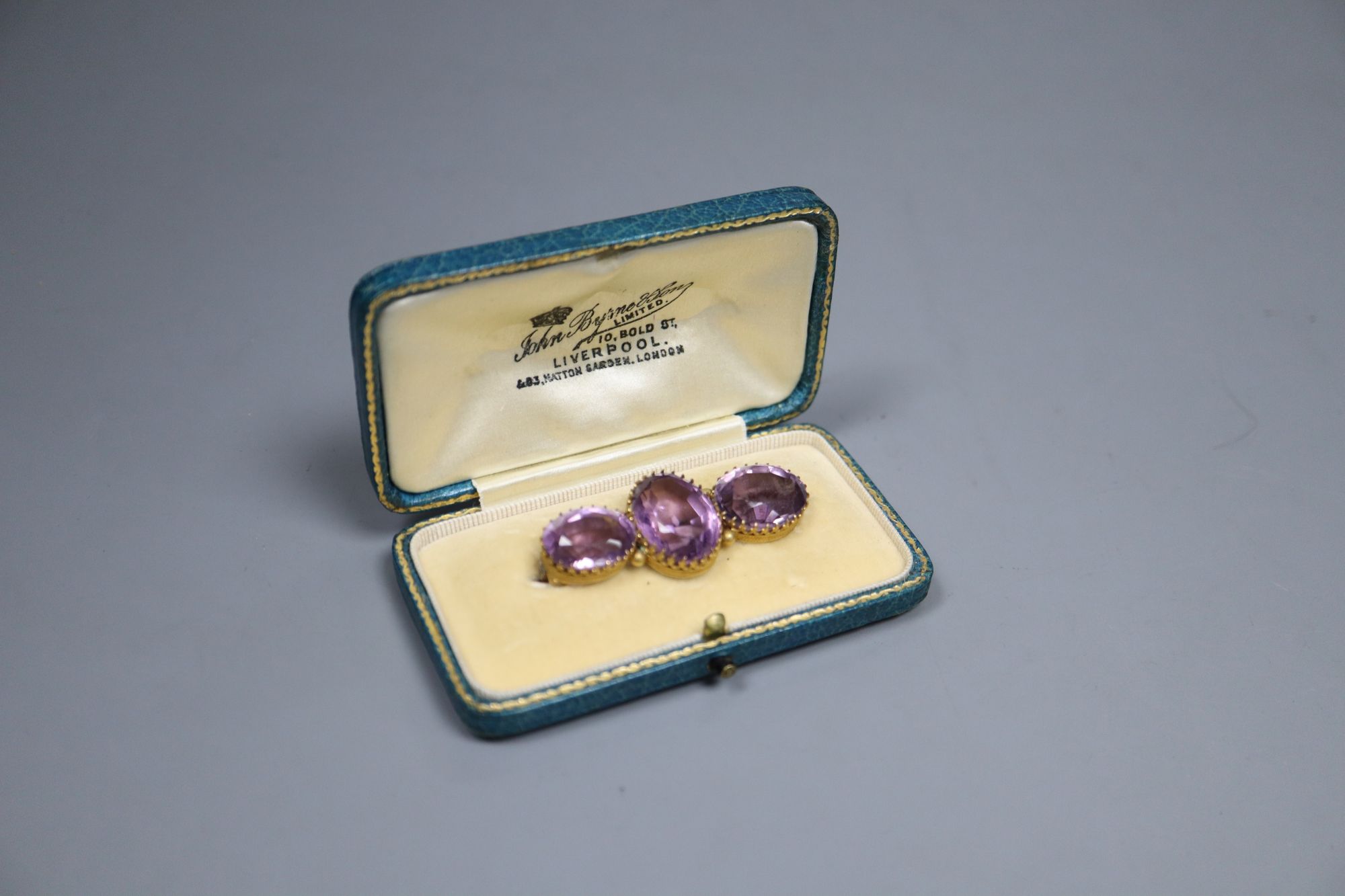 A Victorian yellow metal and three stone amethyst bar brooch, 4.25cm, later cased